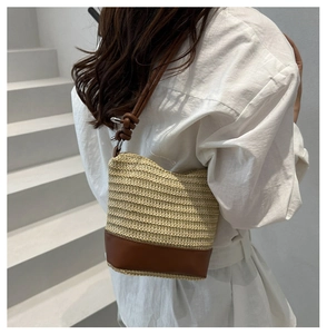 Detail of woven straw bucket bag with brown leather bottom and elegant knotted strap