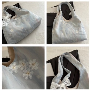 Detail of blue organza tote bag with white flower embroidery and lace bow accent