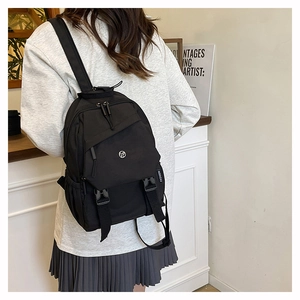 Detail showing the side view of a black nylon backpack with a fashion tag and buckle