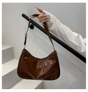 Detailed close-up of a brown glossy crescent hobo bag with high-shine finish and zipper