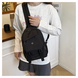 Detail of black nylon chest bag showing multi-zipper compartments and buckle flap pocket