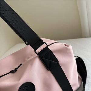 Pink nylon travel duffel bag with black reinforced shoulder straps and fashion logo
