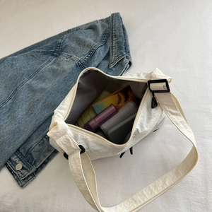 Minimalist white nylon crossbody bag with wide strap showing phone and daily essentials
