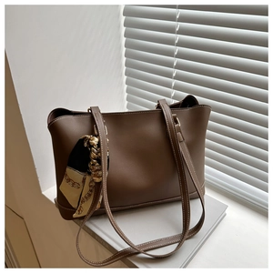 Detail of dark brown tote bag featuring visible stitching and a decorative silk scarf
