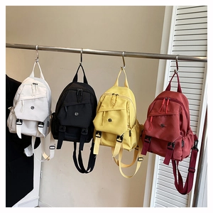 Detail view of four colorful mini nylon backpacks with functional straps and buckles