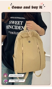 Detail of a lightweight beige nylon backpack with minimal metal logo and vertical zippers