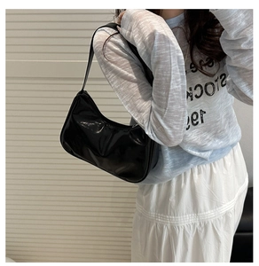 Glossy black hobo shoulder bag shown on model with minimalist side profile view