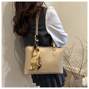 Detail of beige tote bag with smooth texture and vintage silk scarf on the handle