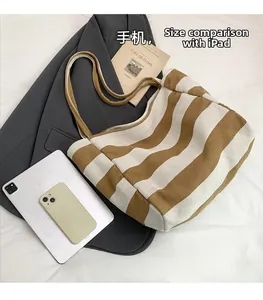 Size comparison of striped canvas tote bag with a tablet, smartphone, and books