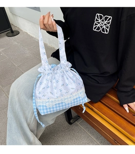 Detailed close-up of floral and plaid patchwork on the drawstring tote bag shoulder strap