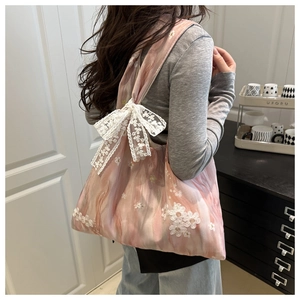 Detail of light pink floral canvas tote bag featuring a large white lace bow decoration