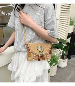 Close-up of straw woven crossbody bag with colorful tassels and ethnic beadwork