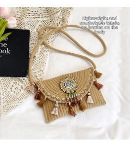 Detailed view of straw crossbody bag with colorful tassels, embroidery and beadwork