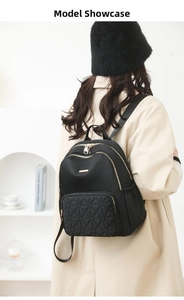 Chic black quilted nylon backpack with gold zippers shown on model in a minimalist setting