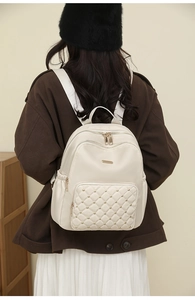 Detailed side view of beige nylon backpack with gold studs and quilted diamond pattern