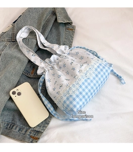 Blue floral and plaid drawstring bag with lace detail and size comparison to phone