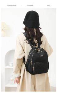 Rear view of a black quilted nylon backpack on a model showing practical capacity and style
