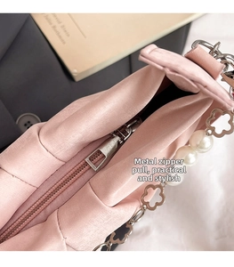 Détail d'un sac rose avec fermeture éclair argentée et bandoulière ornée de perles et fleurs