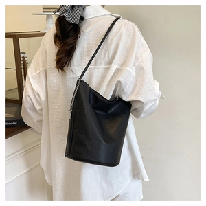 Detail of black lychee texture bucket bag with metal chain and thin shoulder strap