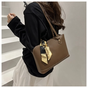 Detail of dark brown leather tote featuring white contrast stitching and a silk scarf accent