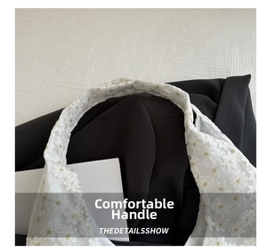 Close-up of white mesh daisy embroidery and wide comfortable handle of the handbag
