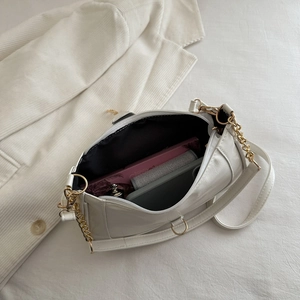 Minimalist white crescent shoulder bag with gold chain and organized interior space
