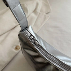 Sleek metallic silver underarm baguette bag with crinkled texture and wide strap
