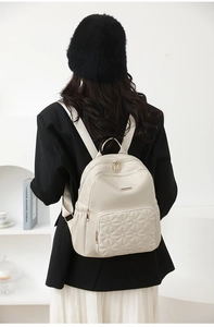 Detail of a creamy white nylon backpack with elegant diamond quilting and zipper pocket
