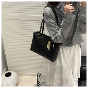 Detail of black leather tote bag with white contrast stitching and silk scarf accessory