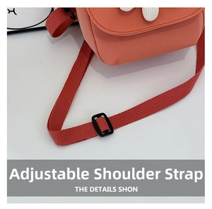 Détail du sac en toile corail montrant la bandoulière tissée réglable avec boucle noire