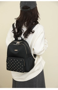 Detail view of nylon backpack with gold-tone rivets and elegant quilted front pocket