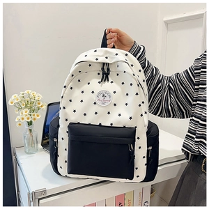 Detail of a white backpack with black star print, front zipper pocket and side pouches