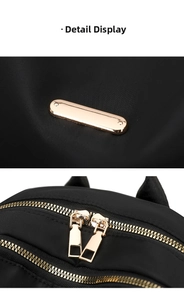 Detail of high-density black nylon fabric with golden polished metal logo plate and zippers