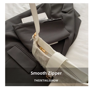 Close-up of smooth gold metal zipper and lace patchwork on white sequins handbag