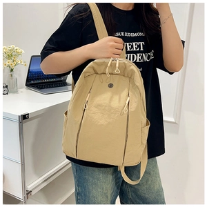 Detail of beige nylon backpack showing vertical zipper pockets and side water bottle holder