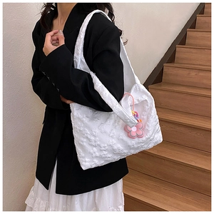 Close-up of white tote bag with floral texture and pink flower pendant decoration