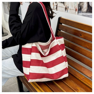 Detail of a large canvas tote bag with bold red and white stripes on a wooden bench