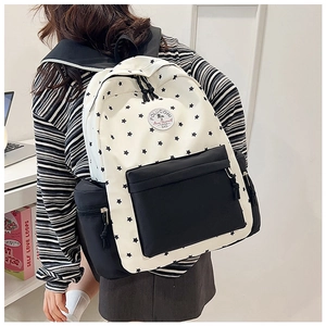 Detailed shot of white nylon backpack featuring black star patterns and brand logo patch