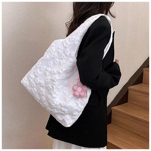 Detail of white 3D floral texture on tote bag with a pink flower charm on the strap
