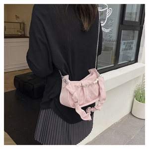 Gros plan du sac plissé rose avec chaîne argentée et perles porté par un mannequin