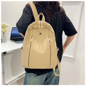 Model wearing a lightweight beige nylon backpack featuring dual vertical zipper pockets
