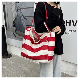Street style shot of a large red and white striped canvas tote bag with red rope handles