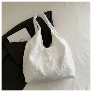 Close-up of white floral lace embroidery on a canvas tote bag with a minimalist design