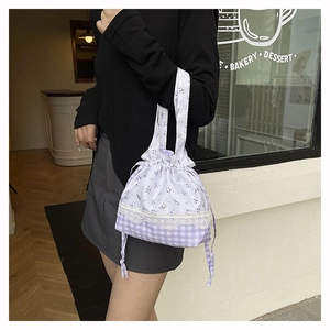 Detail of floral and plaid drawstring handbag with lace trim and dual top handles