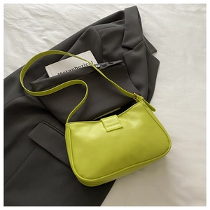 Detail of lime green leather crescent shoulder bag styled on a charcoal grey blazer