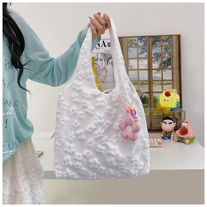 Detailed texture of white floral jacquard fabric on tote bag with pink flower charm