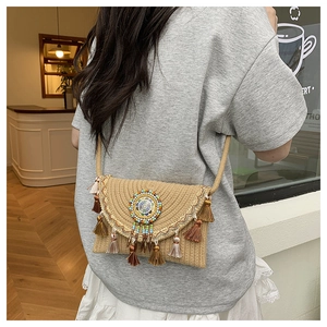 Detail of bohemian woven crossbody bag featuring colorful beads and fringe tassels