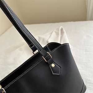 Minimalist black tote bag with white contrast stitching and gold metal hardware detail