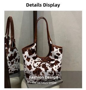Detail of a cow print tote bag with brown leather handles and a centered bow accent