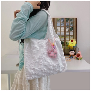 Detail of white textured tote bag with 3D floral pattern and pink flower pendant charm